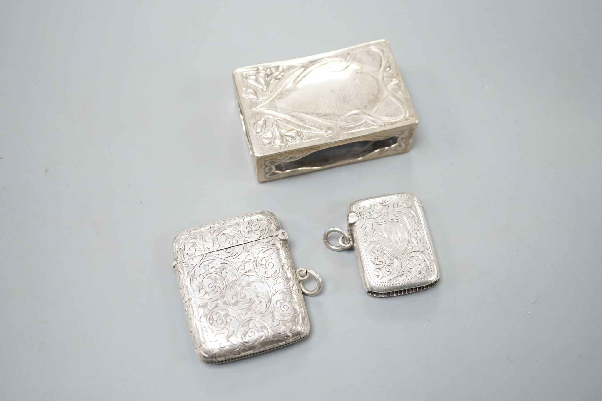 A silver mounted cigarette box, two silver vestas and a silver matchbox sleeve.